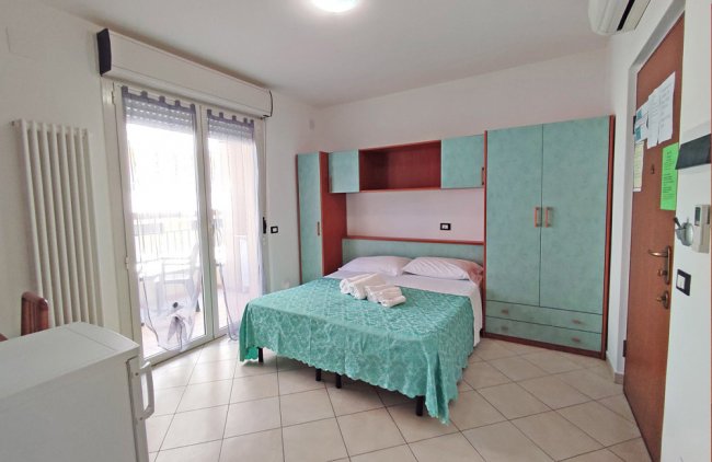 Camera da letto con armadio verde acqua e grande finestra.