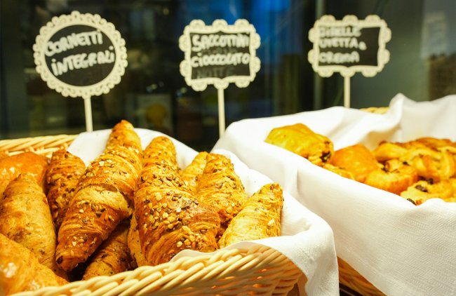 Cesti di croissant integrali e altri dolci con cartelli descrittivi.