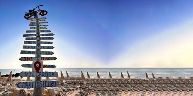 Cartello con indicazioni di località sulla spiaggia.