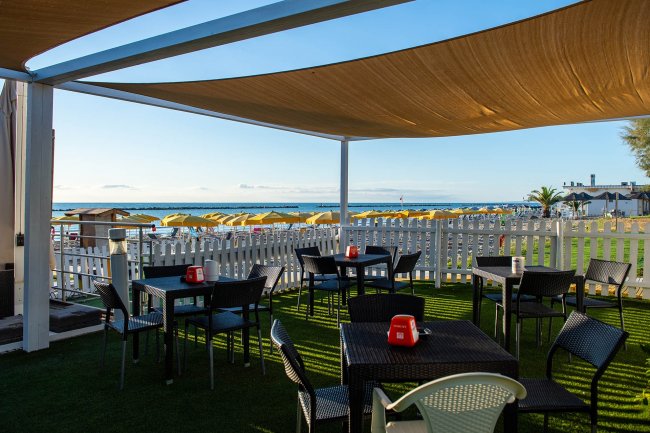 Terrazza con tavolini e vista sul mare.