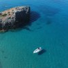 Barca bianca su acque turchesi vicino a una scogliera.