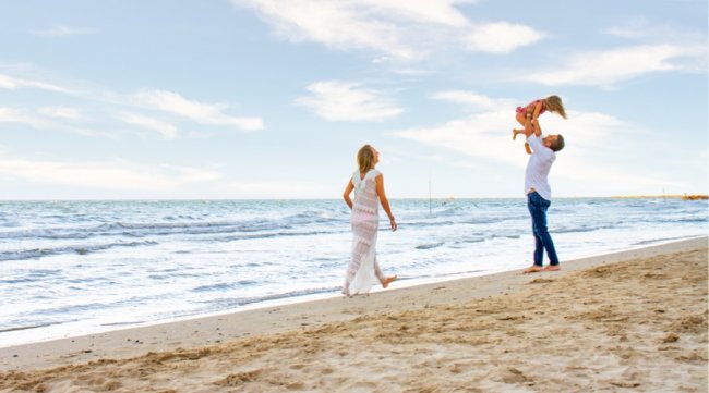 Famiglia felice gioca sulla spiaggia vicino al mare.