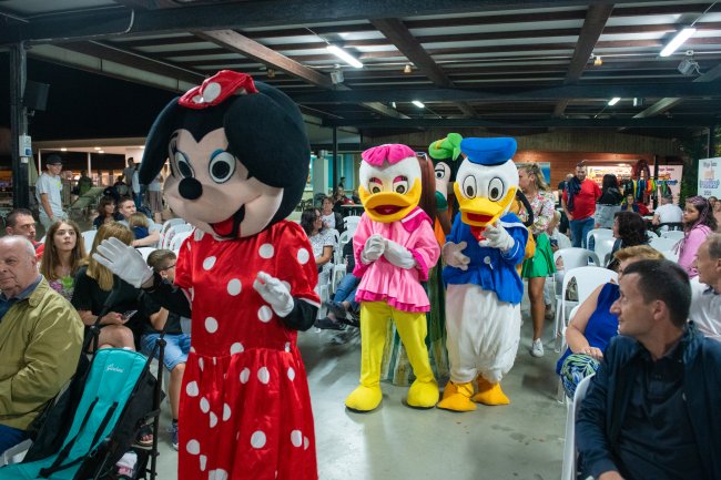 Persone in costume da personaggi animati camminano tra la folla in un evento al coperto.