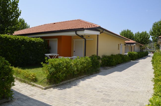 Una villetta con tetto rosso e giardino curato lungo un vialetto.