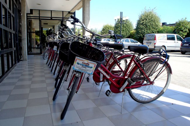 Una fila di biciclette rosse parcheggiate su un marciapiede tile bianco.