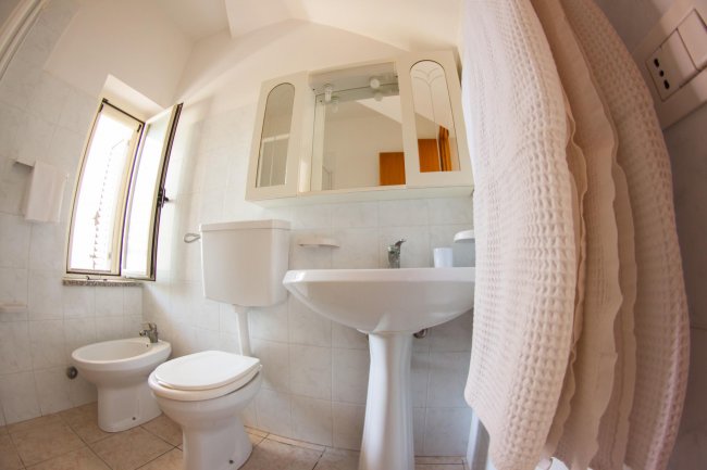 Un bagno con sanitari bianchi, lavabo, e specchio, vista grandangolare.