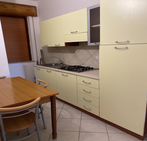 Cucina con mobili chiari e tavolo in legno.
