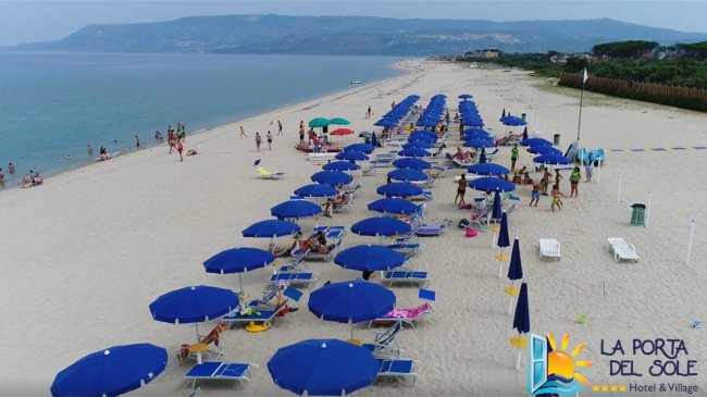 Spiaggia con ombrelloni blu e mare calmo.