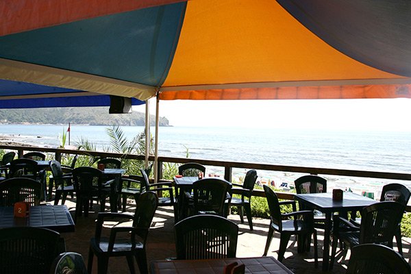 Ristorante all'aperto con tavoli e sedie, vista sul mare.