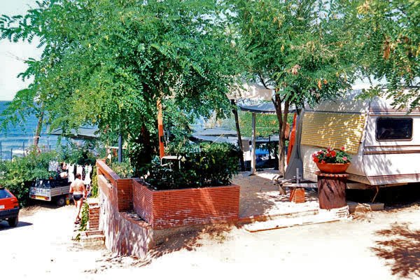 Un'area campeggio con roulotte, alberi e vista mare.