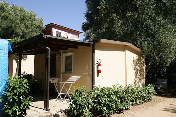 Esterno di un bungalow con veranda e piante.