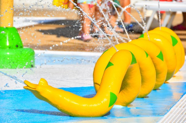 Struttura gialla a forma di serpente in un parco acquatico spruzza acqua.