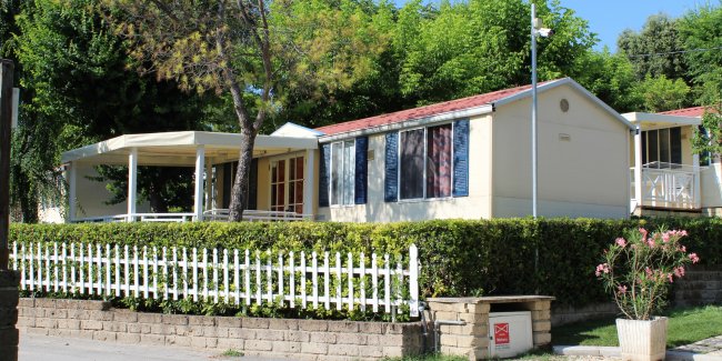 Casa prefabbricata con recinzione bianca e verde all'aperto.