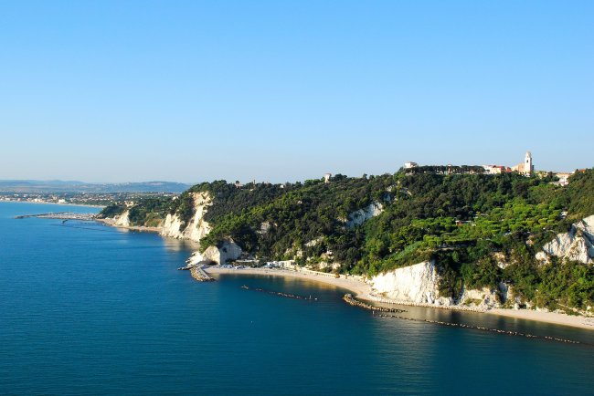Costa rocciosa con scogliere bianche e vegetazione, vista sul mare.