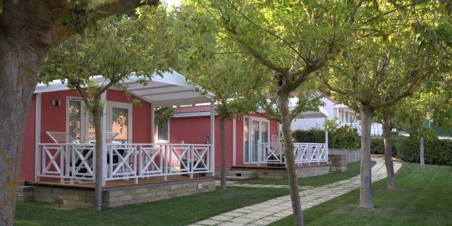 Case mobili rosse con terrazza e giardini alberati.