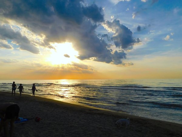 Tramonto su una spiaggia con persone che camminano.