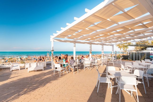 Terrazza di un bar fronte mare con sedie e tavoli.