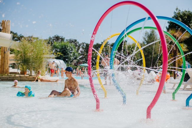 Una piscina con giochi d'acqua e bambini che giocano.