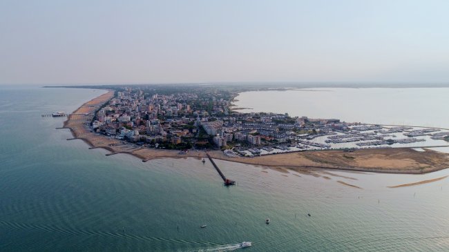 Vista aerea di una città costiera con spiaggia e porto.