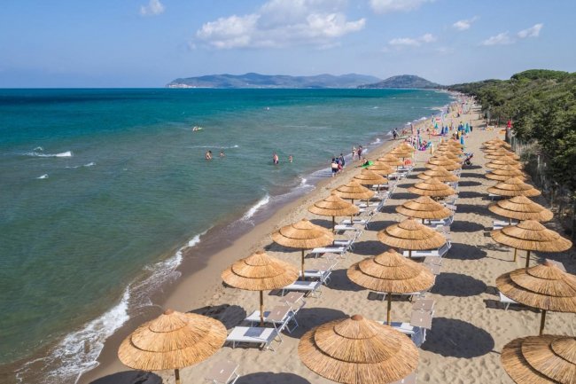 Spiaggia con ombrelloni e mare sullo sfondo.