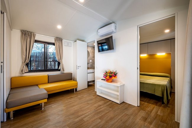 Soggiorno moderno con divano giallo e TV.