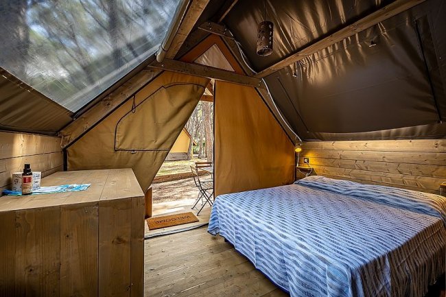 Stanza glamping con letto, vista esterna aperta.