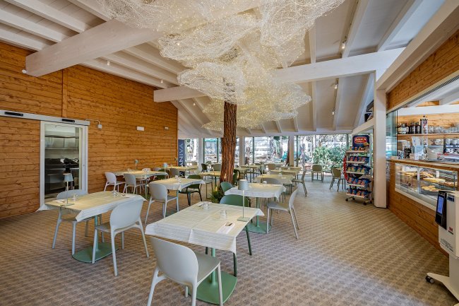 Sala con tavoli e sedie bianche e verdi, soffitto decorato.