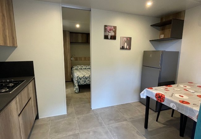 Interno di una cucina con tavolo decorato e vista su una stanza da letto.