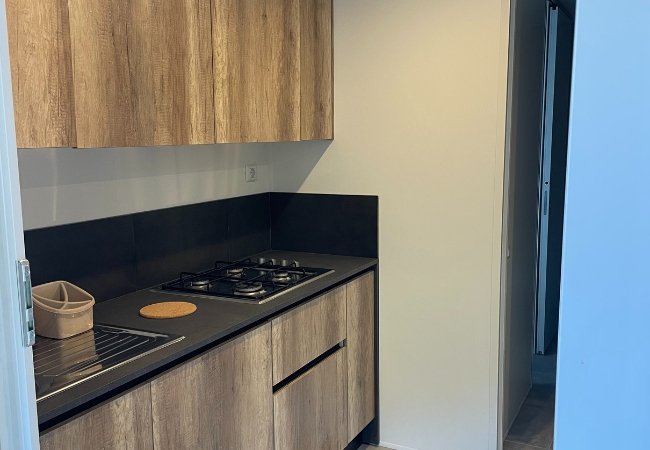 Cucina moderna con piano cottura nero e mobili in legno chiaro.