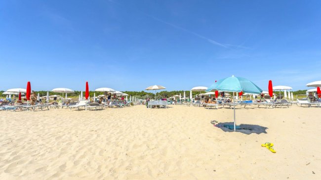 Una spiaggia con ombrelloni rossi e bianchi.