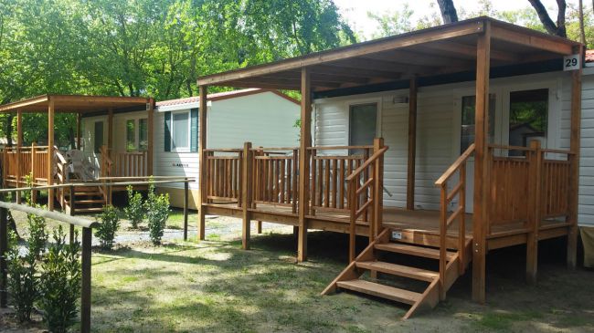 Due case mobili con verande in legno in un'area verde.
