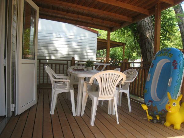 Veranda con tavolo e sedie bianche. A destra un gonfiabile e un giocattolo giallo.