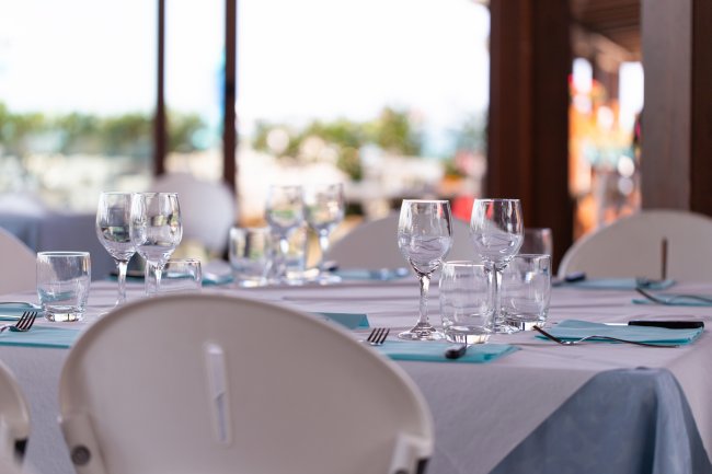 Tavola apparecchiata con bicchieri e tovaglioli azzurri in un ristorante all'aperto.