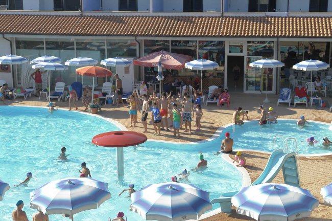 Dettaglio della piscina con persone che nuotano e intrattenimento sul bordo.