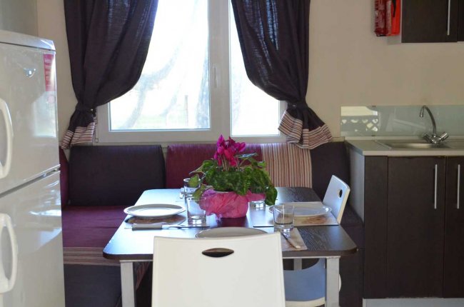 Cucina con tavolo apparecchiato, lampada e pianta viola al centro.