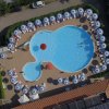 Una piscina a forma irregolare con ombrelloni bianchi disposti intorno.