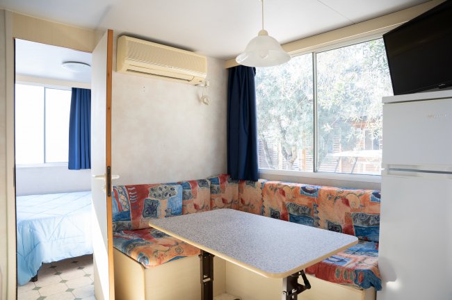 Interno di una casa mobile con tavolo, finestra e letto.