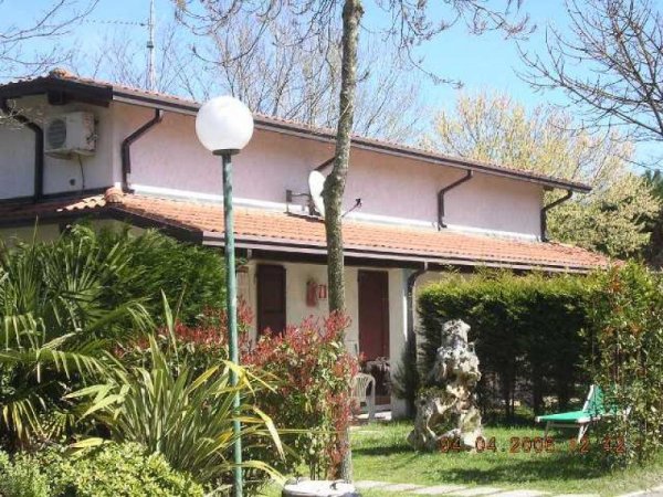 Un edificio con tetto rossiccio circondato da alberi e cespugli.