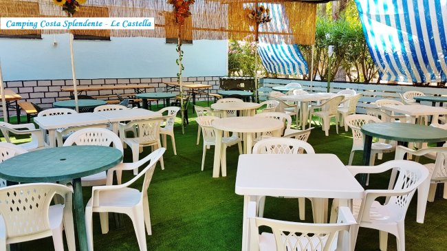 Patio coperto con tavoli e sedie in plastica.