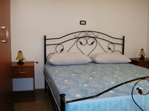 Camera da letto con letto matrimoniale, testiera in ferro battuto e comodini.