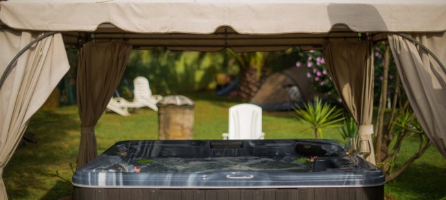 Vasca idromassaggio sotto un gazebo in giardino.