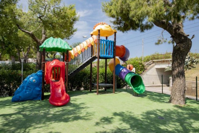 Parco giochi colorato con scivoli tubolari e strutture di arrampicata.