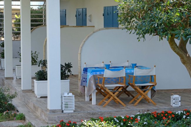 Portico con tavolo apparecchiato e sedie in legno.