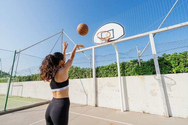 Donna tira a canestro su campo da basket esterno.
