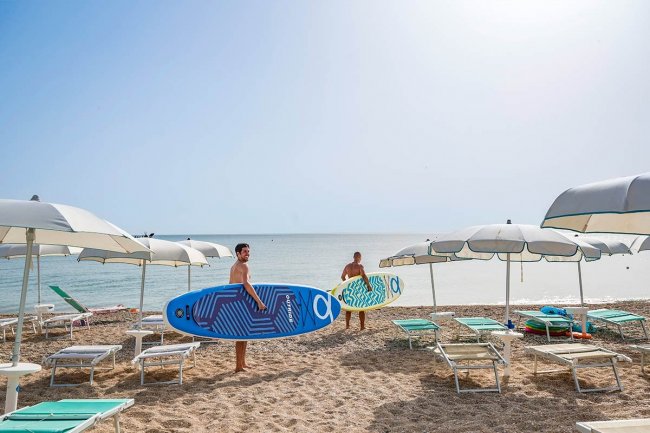 Due persone con tavole da surf sulla spiaggia.