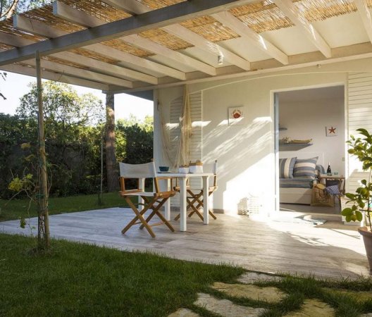 Veranda con tavolo e sedie vicino a un giardino.