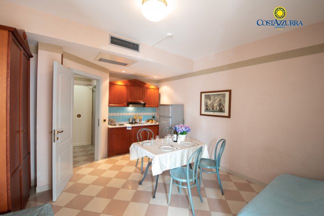 Cucina con tavolo apparecchiato, fiori al centro e quadro appeso al muro.