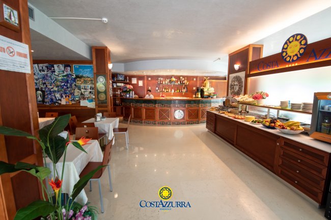 Interno di un ristorante con tavoli apparecchiati e un banco bar.