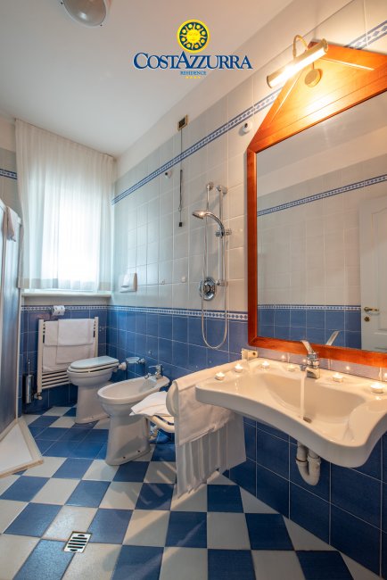 Bagno con piastrelle blu e bianche, lavabo, bidet e doccia.
