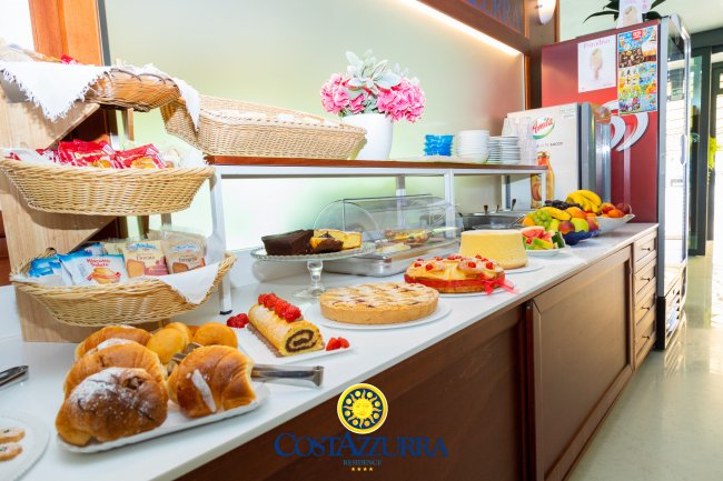 Un buffet con dolci assortiti su un tavolo, decorato con cestini e fiori rosa.